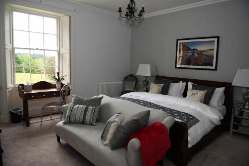 兰代洛Llwynhelig Manor的一间卧室配有一张床、一张沙发和一个窗口