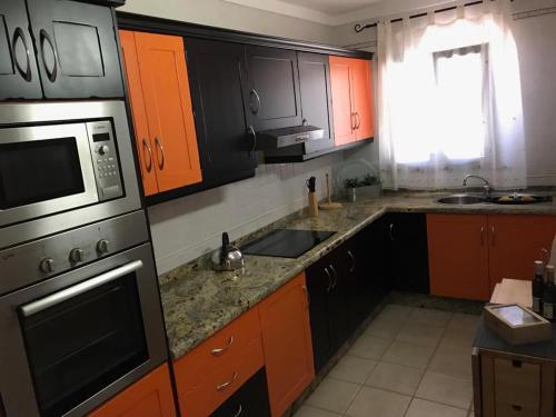 圣地亚哥海滩Apartamento El Cascajo的厨房配有橙色和黑色橱柜以及水槽