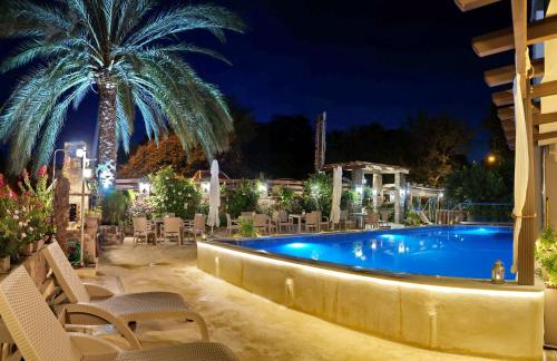 Loutrópolis Thermís加拉基奥阿斯特里伊酒店的夜间游泳池,带椅子和棕榈树