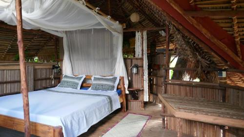 贝岛Hotel Ambalamanga的一间卧室配有天蓬床和长凳