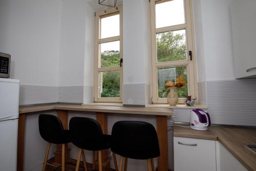 克宁Prenoćište Kastel的厨房设有三扇窗户和一个带椅子的柜台。