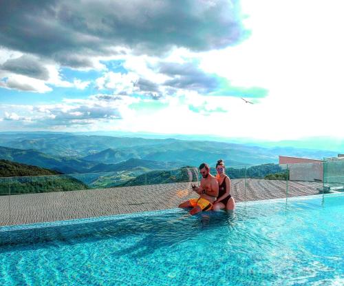 科帕奥尼克SM Apartments Kopaonik的两人坐在泳池边欣赏美景