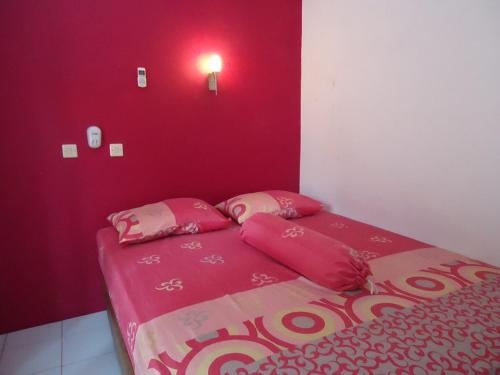庞岸达兰Kancil homestay的红色卧室配有带粉红色床单和枕头的床