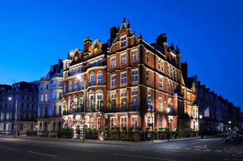 伦敦红色康乃馨肯辛顿里程碑酒店的街上的一座灯火通明的建筑