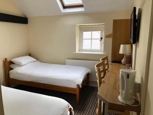 科尔福德Butchers Arms的客房设有两张床、一张桌子和一扇窗户。