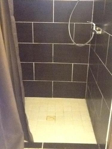 东方湾Studio 03 vue mer Orient Bay的浴室铺有瓷砖地板,设有黑色瓷砖淋浴间。