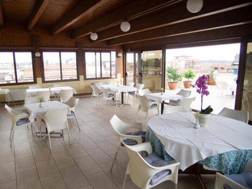 Taglio di Po特萨林酒店的餐厅设有白色的桌椅和窗户。