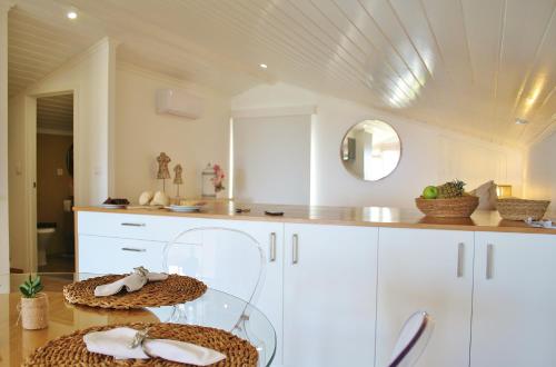 坎普自由鎮374 CK Seaside Guest House的厨房配有白色橱柜和一张带两个篮子的桌子