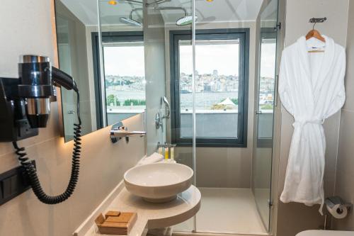 伊斯坦布尔MEG HOTEL的带淋浴和盥洗盆的浴室以及电话。
