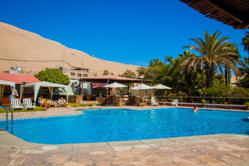 伊察DM Hoteles Mossone - Ica的度假村内带椅子和遮阳伞的游泳池