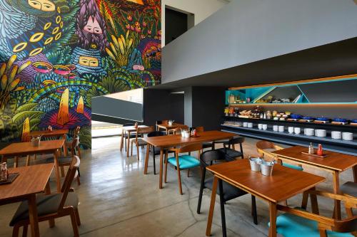 三宝垄ARTOTEL Gajahmada Semarang的餐厅设有木桌和色彩缤纷的壁画