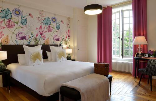 GuéronChâteau Saint Gilles的卧室配有一张白色大床和花卉壁纸