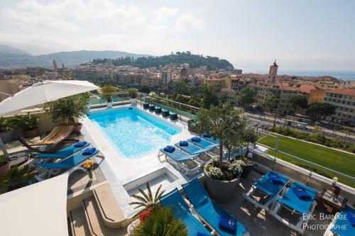 尼斯阿斯顿斯卡拉酒店的一个带蓝色椅子的游泳池,一个城市