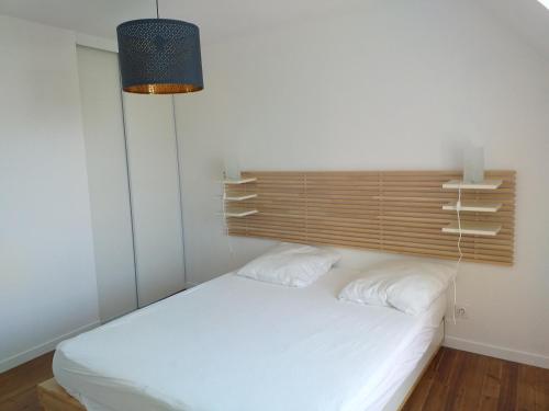 庞马尔LA ROLANDE的卧室配有白色的床和木制床头板