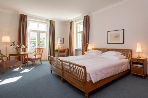 博尔扎诺劳伦公园酒店的一间卧室配有一张大床和一张桌子及椅子
