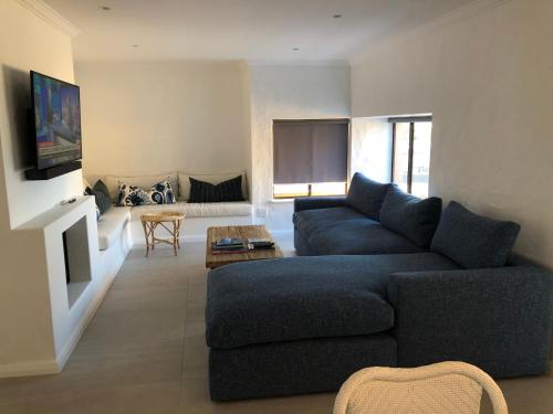 普利登堡湾The Sanctuary Penthouse的客厅配有蓝色的沙发和电视