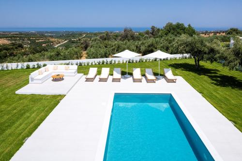 RoúpaiVilana White Elegant Villa的一个带躺椅的室外游泳池和一个游泳池