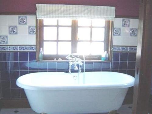 泰克利白宫酒店的带窗户的浴室内的白色浴缸