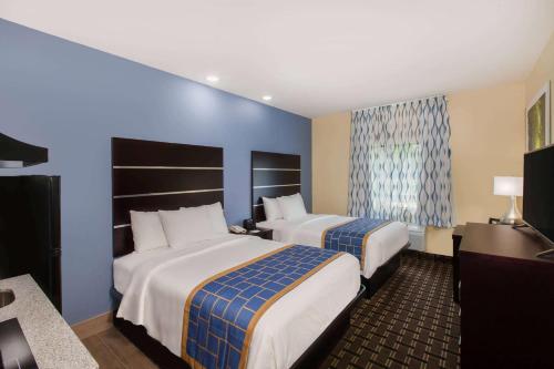 巴吞鲁日Days Inn by Wyndham Baton Rouge Airport的两张位于酒店客房的床,拥有蓝色的墙壁