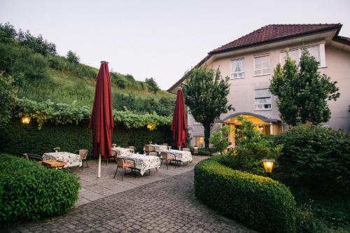 玛特丁恩Landhaus Keller - Hotel & Restaurant的一个带桌子和红色遮阳伞的庭院和一座建筑