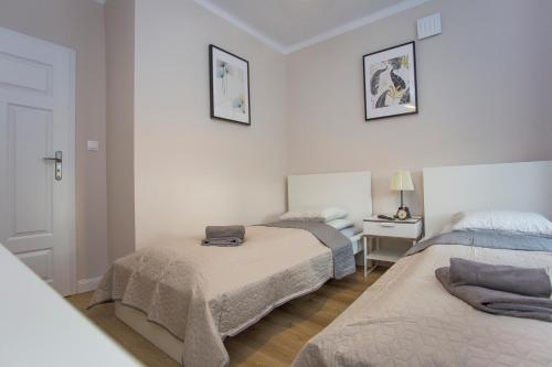 比亚韦斯托克CR Apartament przy Rynku Sienkiewicza 6的一间卧室配有两张床和一张带台灯的桌子