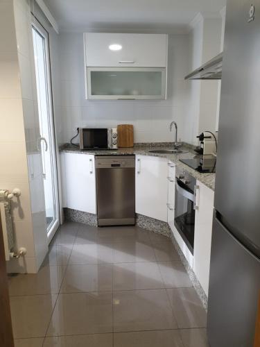 卢戈APARTAMENTOS PORTA NOVA的厨房配有白色橱柜和不锈钢用具