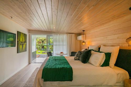 怀蒂昂格Wairua Lodge - Rainforest River Retreat的一间卧室设有一张带木制天花板的大床