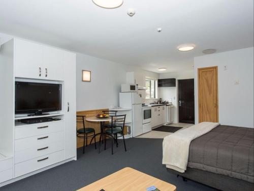 瓦纳卡克里尔布鲁克服务式汽车旅馆&公寓的一间卧室配有一张床,厨房配有桌子