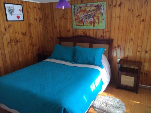 圣地亚哥Casa en Santiago equipada的一间卧室配有一张带蓝色床单和木墙的床。