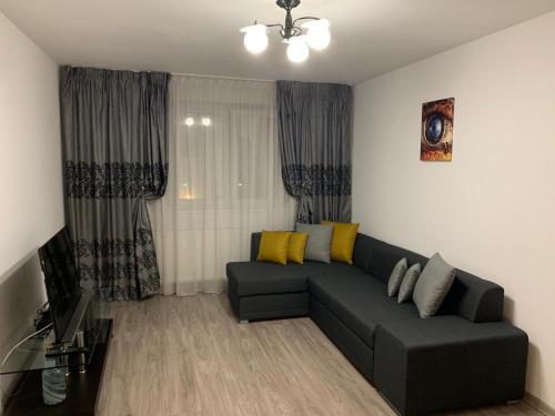 布加勒斯特Apartament Cristina的客厅配有黑色沙发和黄色枕头