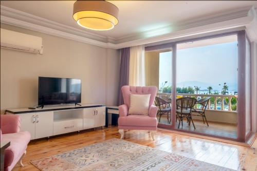 费特希耶Fethiye City Aparts的一间带电视和椅子的客厅以及一个阳台
