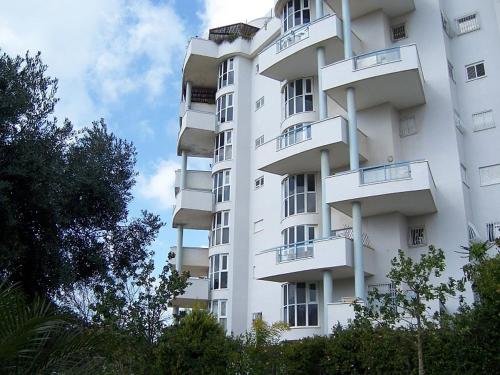 内坦亚Ramat Poleg, walk to beach的带阳台的白色公寓大楼