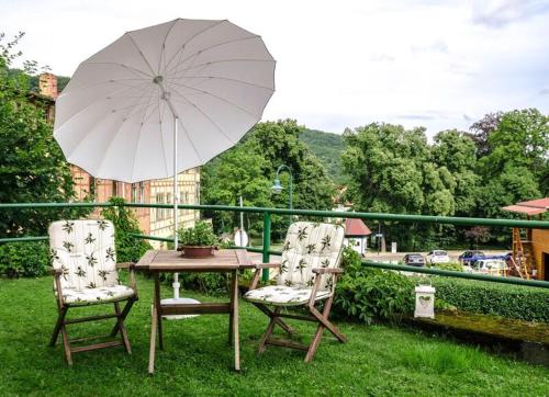 塔勒Ferienwohnung Christine的阳台配有一张桌子和两把椅子及一把遮阳伞