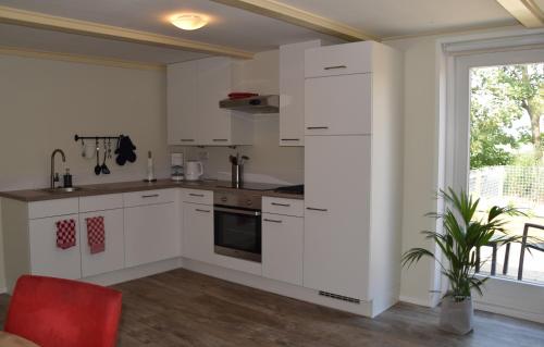 莱米尔Het Friese Landschap的厨房配有白色橱柜和红色椅子