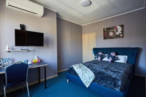 库马iMotel Cooma (in town)的一间卧室配有蓝色的床、一张书桌和电视。