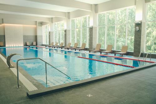 尤尔马拉Daina Jurmala Beach Hotel的大楼内带椅子的大型游泳池