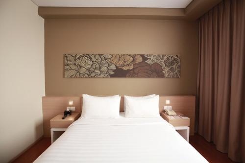 当格浪Swiss-Belinn Airport Jakarta的卧室配有白色的床和墙上的绘画作品