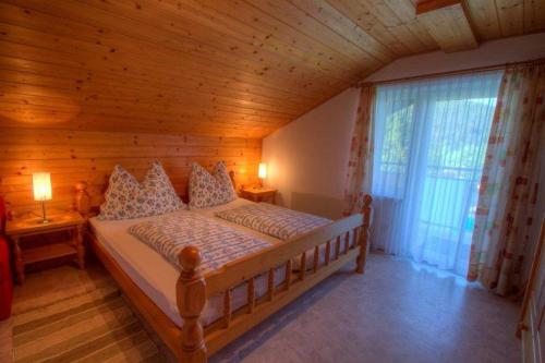 法克湖Haus am Wald的木制客房内的一间卧室,配有一张床