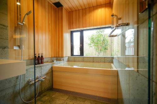 东京Kaminarimon Ryokan的带浴缸的浴室和窗户。