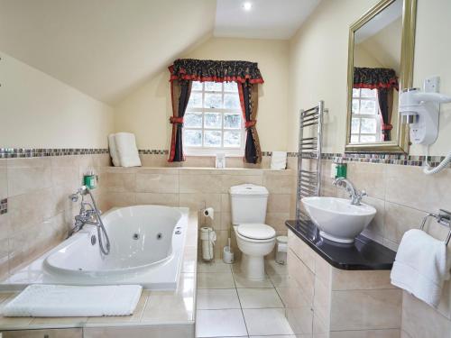 锡廷伯恩赫普斯特德之家餐厅酒店的带浴缸、卫生间和盥洗盆的浴室