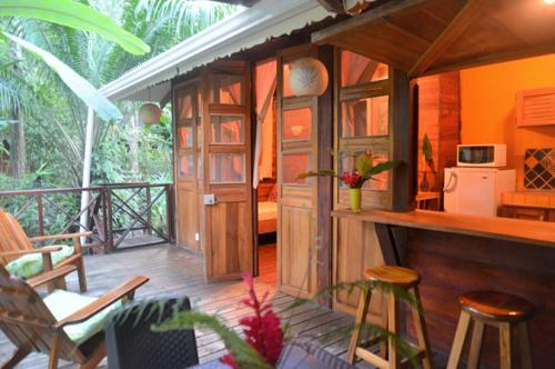别霍港Pachamama Jungle River Lodge - Punta Uva的带椅子的门廊和厨房的客房