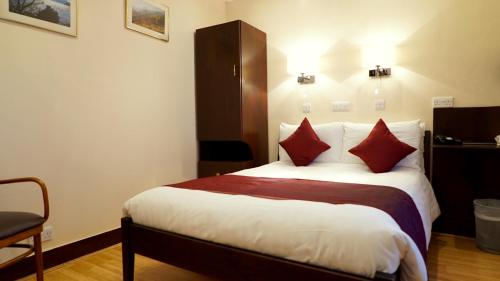 伦敦La Gaffe - Bed and Breakfast的酒店客房配有一张带红色枕头的大床