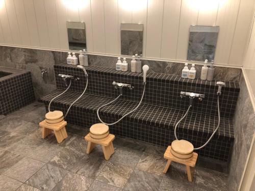 周南市光市山丘酒店的浴室设有3个水龙头和3个木凳