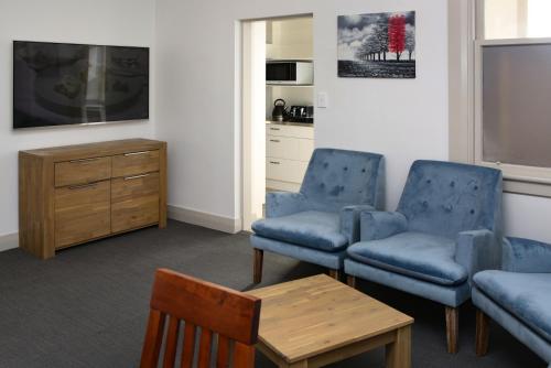 奥克兰The Prospect of Howick Accommodation的客厅配有2把蓝色椅子和桌子