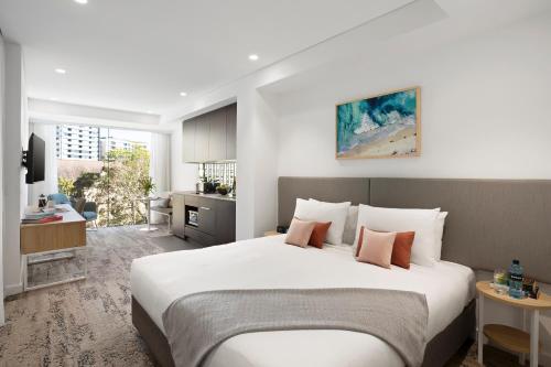 悉尼Quest North Sydney的一间带白色大床的卧室和一间厨房