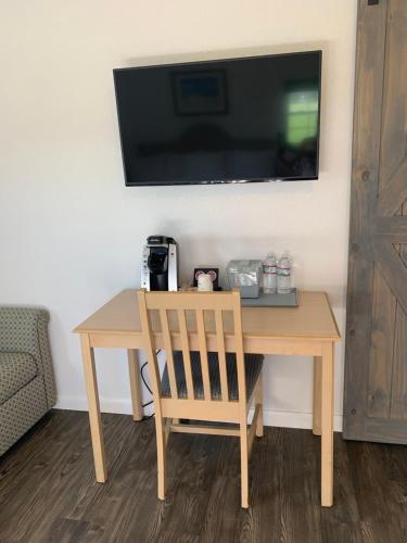 开普查尔斯Cape Motel的一张木桌、椅子和墙上的电视