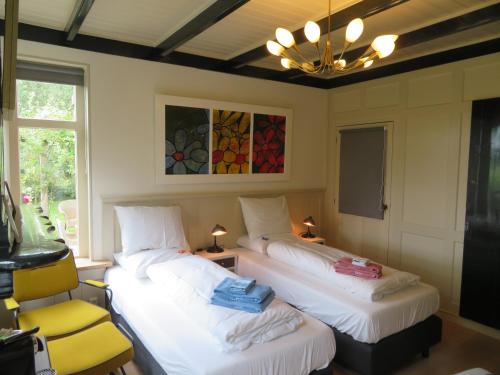 GorredijkB&B Singelstate的客房设有两张床、一把椅子和吊灯。