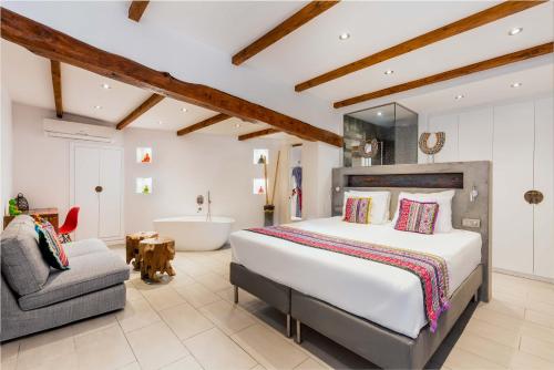 圣埃乌拉利亚伊比扎森酒店的一间卧室配有一张床、浴缸和椅子