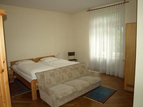 巴特基辛根Hotel Villa Arnold的一间卧室配有一张床、一张沙发和一个窗口