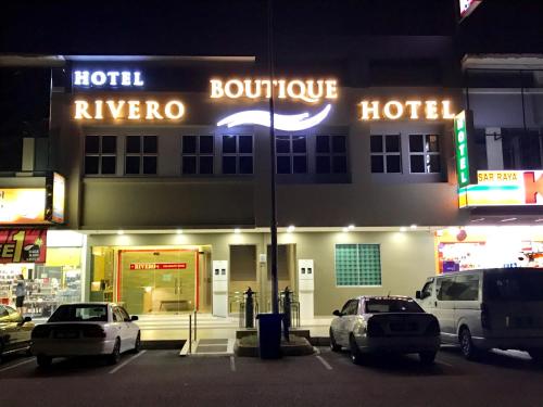 芙蓉RIVERO BOUTIQUE HOTEL Seremban 2的一家晚上停在外面有车辆的酒店